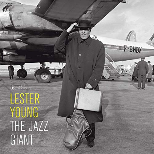 Lester Young in hat and coat, holding a suitcase by an airplane.