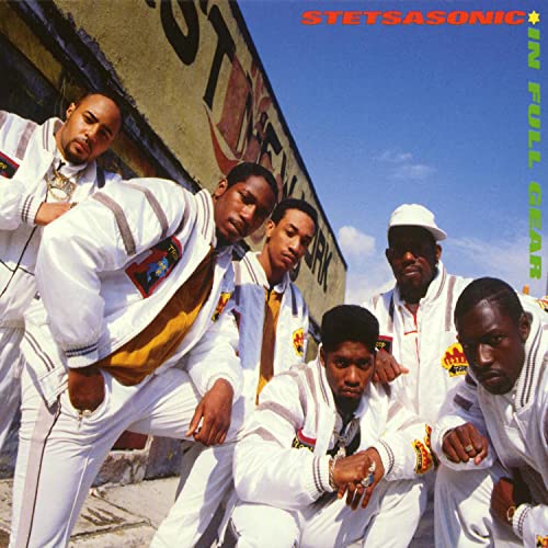 Stetsasonic group portrait in white jackets against a brick wall.
