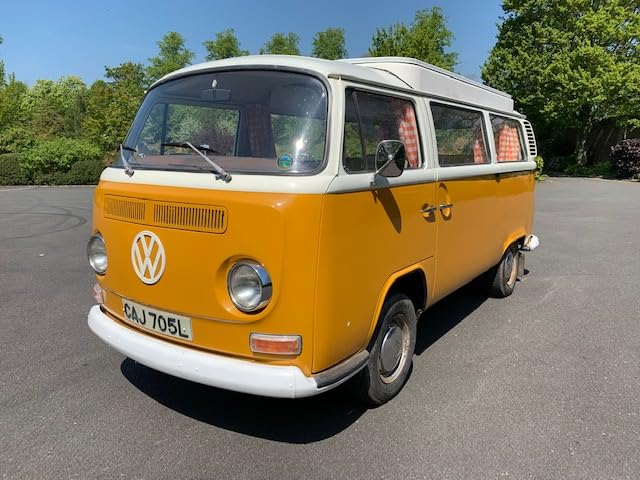 Yellow and white vintage Volkswagen camper van parked on asphalt.