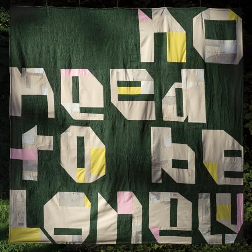 Quilt displaying the text "No Need To Be Lonely" in patchwork blocks.
