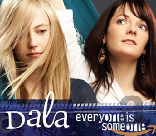 Two women, one blonde and one brunette, pose against a blue patterned background.