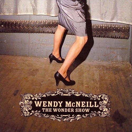 CD cover: legs in heels against a textured wall, ornate frame.