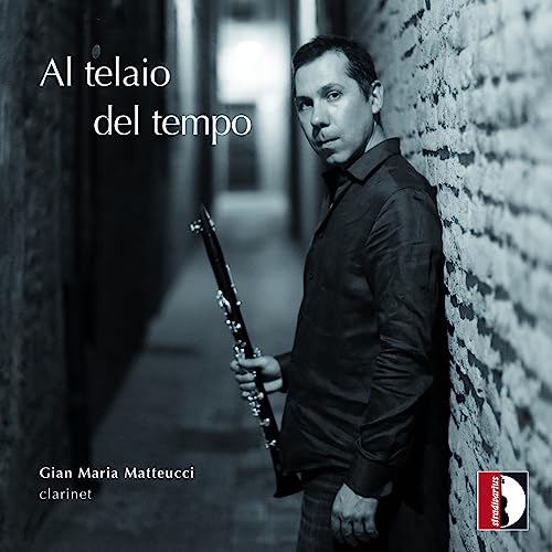 Man with clarinet stands in a narrow, textured alleyway.
