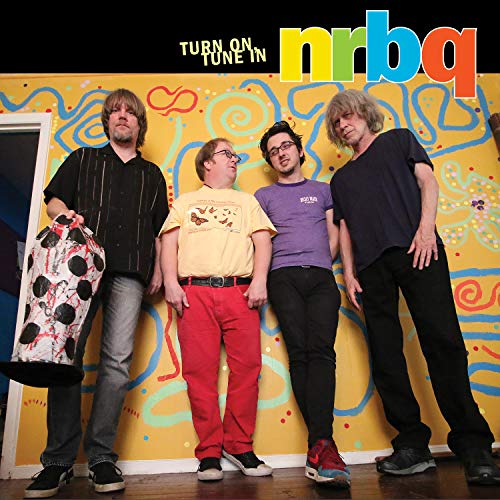 Four men posing in front of a colorful, painted wall.