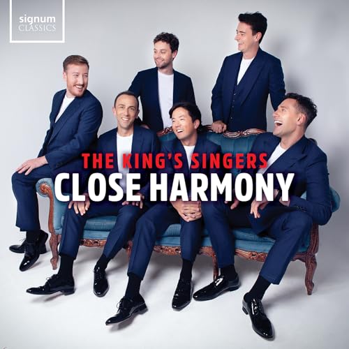Six men in suits pose on a blue sofa for album cover.