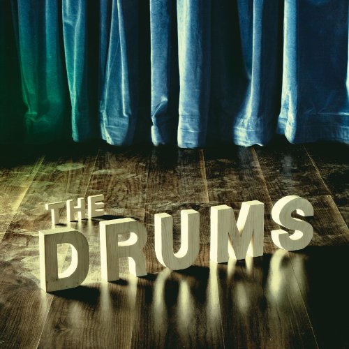 Album cover for "The Drums" with large, white letterforms on a wood floor.