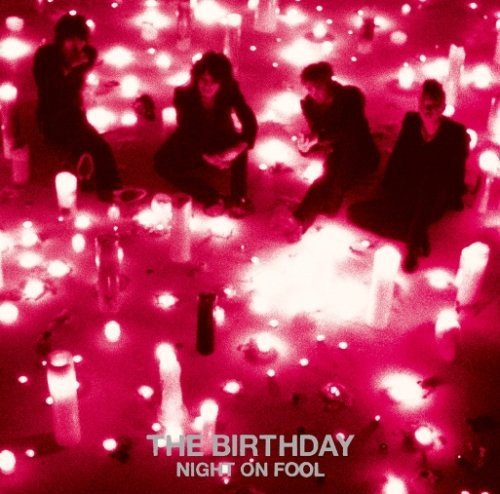 Red-tinted album cover showing four people sitting among many glowing candles.