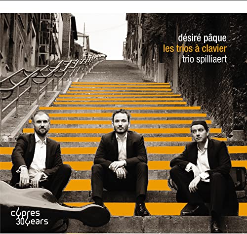 Three musicians sit on orange stairs before a grayscale street scene.