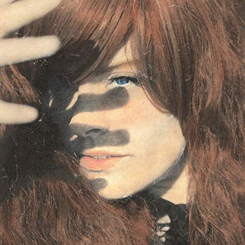 Close-up of a woman with long brown hair, partially obscured by shadows.