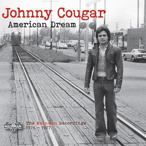 A man in a leather jacket stands on railroad tracks in this black-and-white photo.