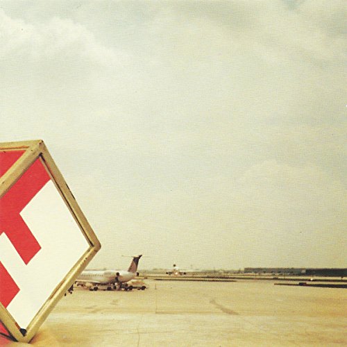 Airplane on a runway with a red and white angled sign in foreground.