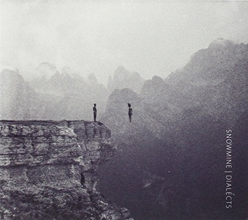 A person stands on a cliff edge facing a figure floating in the misty mountains.