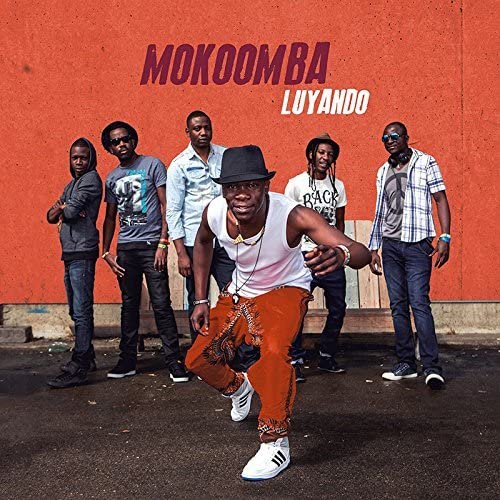 Mokoomba band members posing against a vibrant orange wall for album cover.
