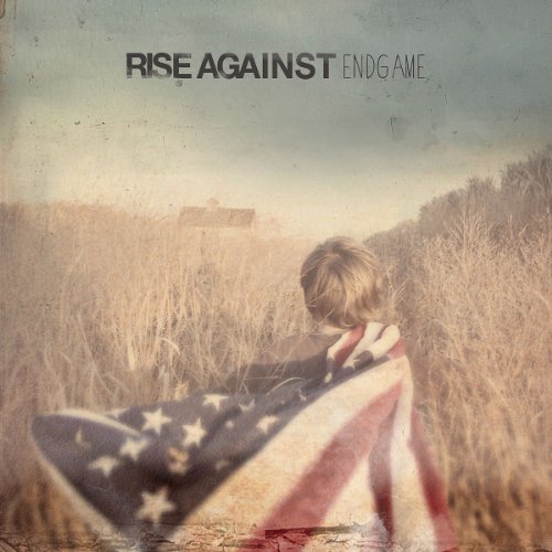 Child wrapped in an American flag, standing in a field.