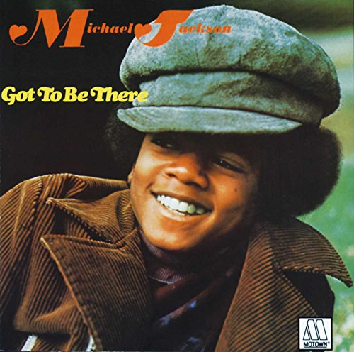 Young Michael Jackson smiling, wearing a flat cap and brown corduroy jacket.