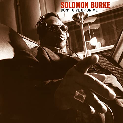 Solomon Burke wearing headphones and sunglasses, reaching toward the camera in a sepia-toned photo.
