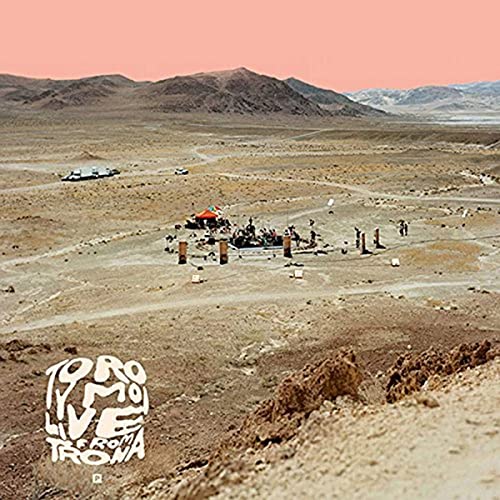 Desert landscape with a small stage and band setup, album art.