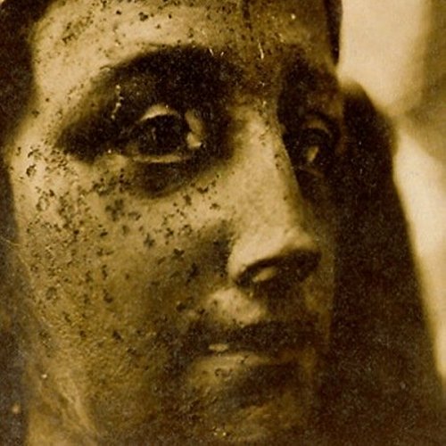 Close-up of a woman’s face with dark, textured, sepia-toned portraiture.