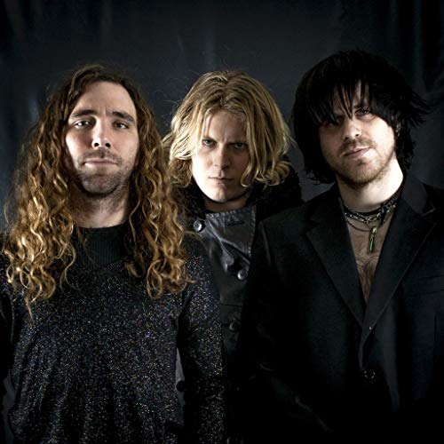 Three men with long hair pose against a dark background.