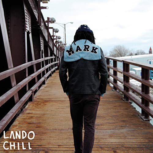 Person with “MARK” on jacket walking away on a wooden bridge.
