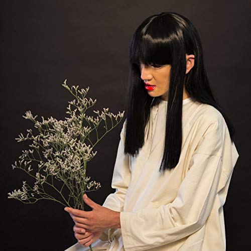 Woman with long black hair holds a bunch of small white flowers.