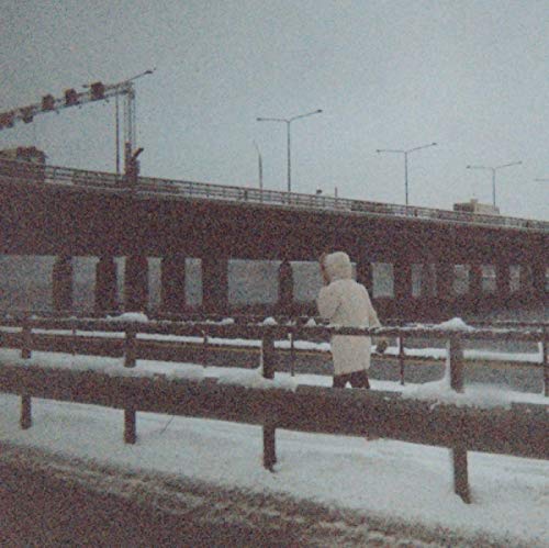 Black and white photo of a person on a snowy bridge.