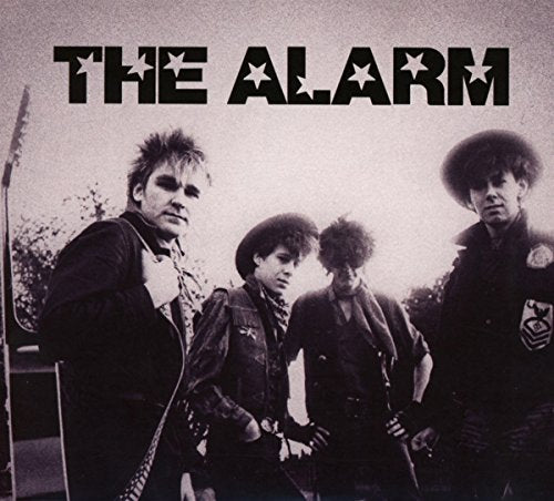 Black and white photo of four men, likely a band, with spiky hair.