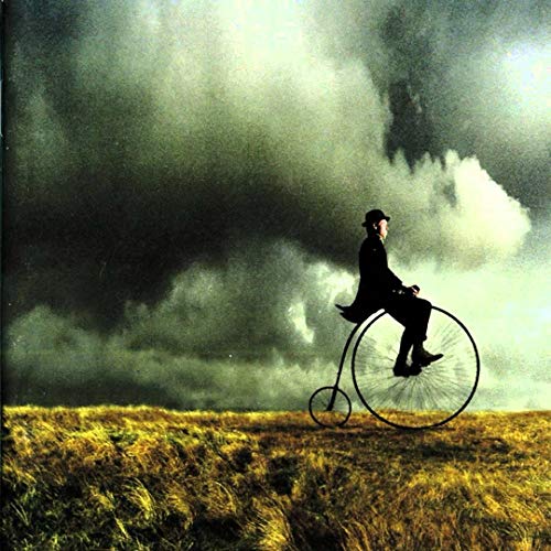 Man on a large-wheeled bicycle silhouetted against a stormy sky.
