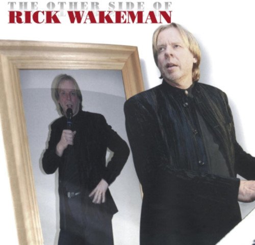 Rick Wakeman standing by a mirror, looking into it with a microphone.