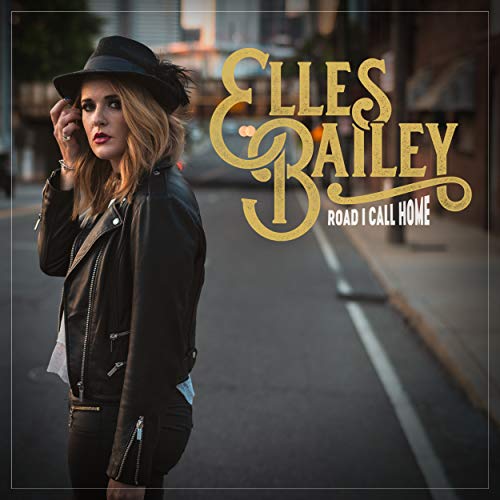 Elles Bailey wearing a hat and leather jacket standing on a city street.