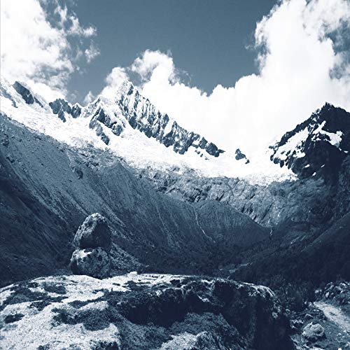 Snow-capped mountains and a rocky foreground in a blue-toned landscape.
