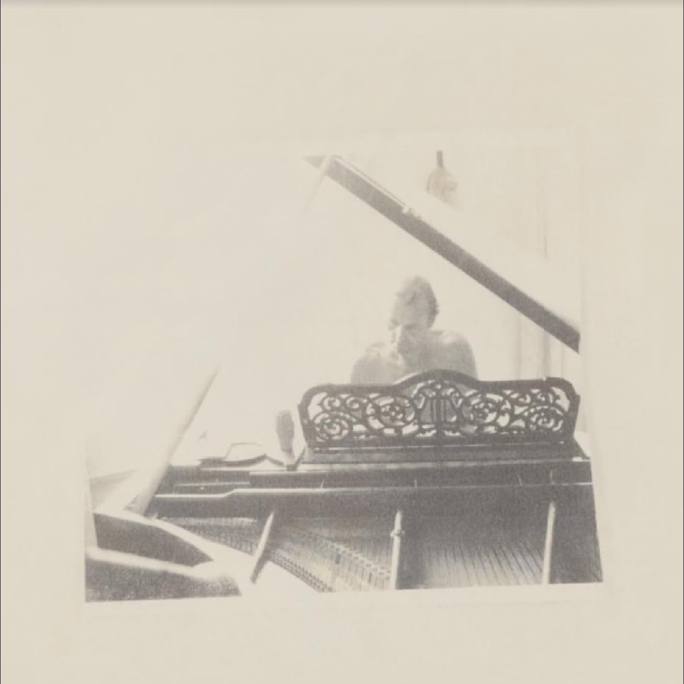 Black and white photo of a man at a piano, blurred image.