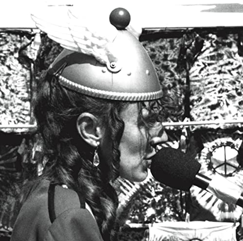 Black and white profile photo of a woman wearing a winged helmet and microphone.