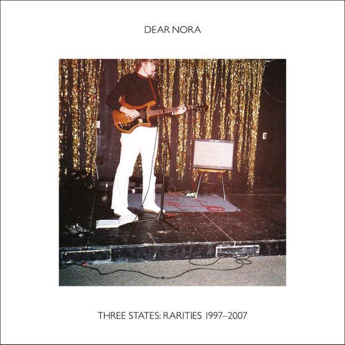CD cover: musician playing guitar on a stage with gold curtains.