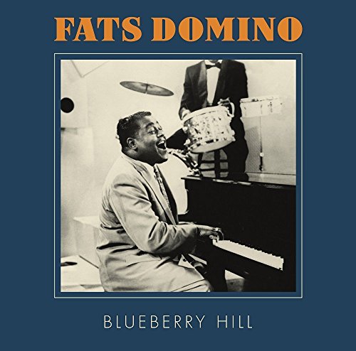 Fats Domino playing piano with a drummer in a vintage photograph.