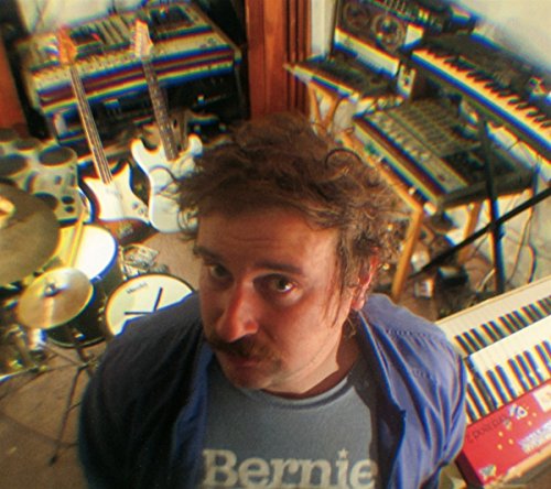 Man with mustache in studio surrounded by musical instruments, distorted effect.