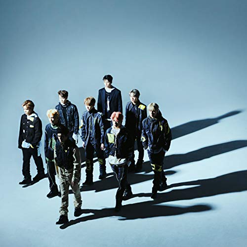 Nine members of NCT 127 walking forward against a plain blue background with shadows.