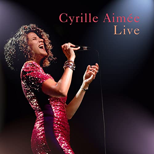 Cyrille Aimée singing into a microphone on a stage, album cover.