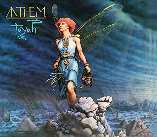 A winged woman with red hair stands on a rock above a pyramid landscape.