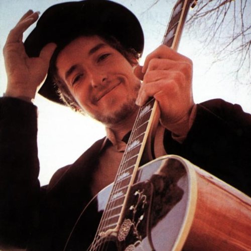 Bob Dylan with a guitar, wearing a hat, against a pale sky.