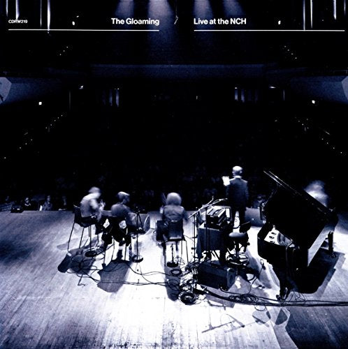 The Gloaming performing on a dimly lit stage with a piano and audience.