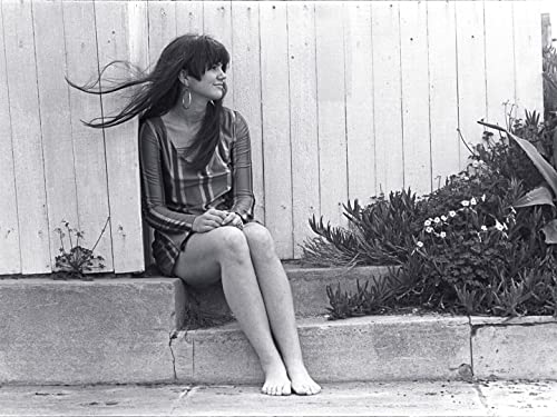Black and white photo of Linda Ronstadt sitting, hair blowing in the wind.