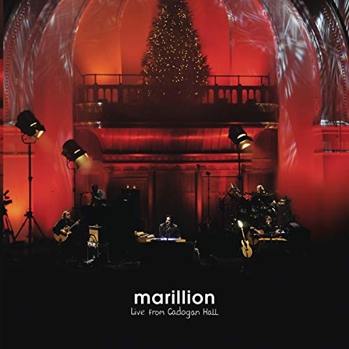 Marillion live concert stage with musicians, red lighting, and a Christmas tree.