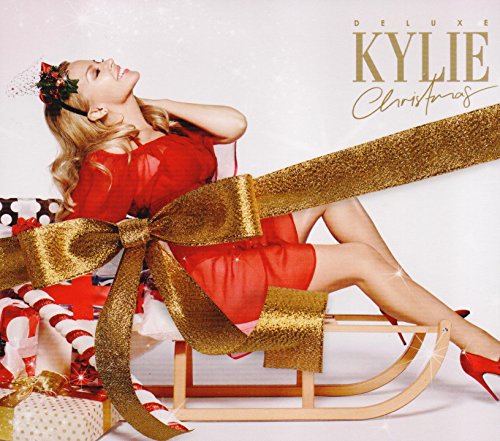 Kylie Minogue in red dress on a sled with gold ribbon and gifts.