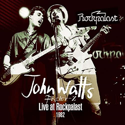 John Watts and a guitarist performing live on stage in 1982.