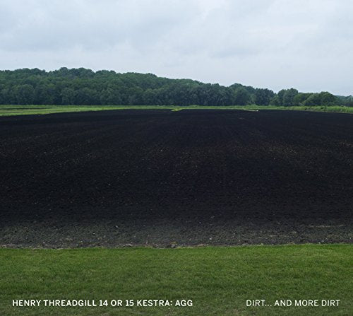 Dark plowed field under a cloudy sky with distant green trees.