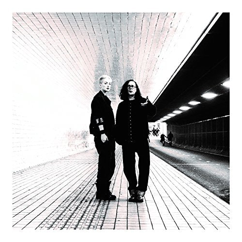 Two people stand in a tiled tunnel, black and white image.