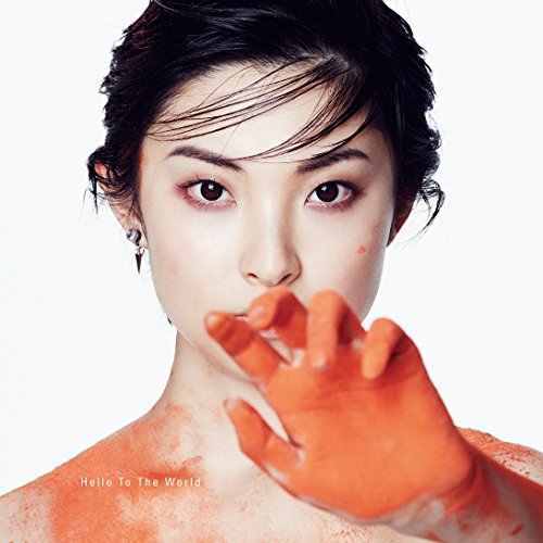 Close-up portrait of a woman with orange paint on face and hand.