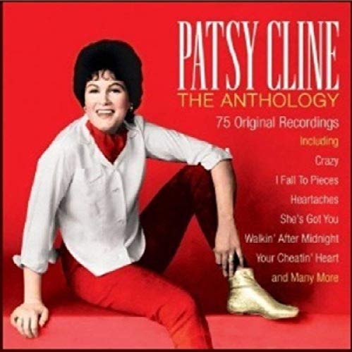 Patsy Cline sits on a red background wearing a white shirt and red pants.
