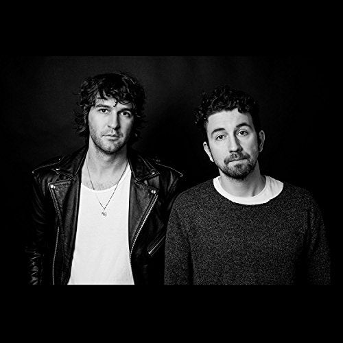 Black and white portrait of two men against a dark background.